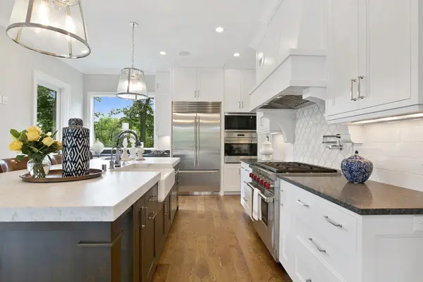White kitchen renovation with a farmhouse sink and stone counters