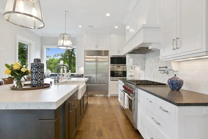 White kitchen renovation with a farmhouse sink and stone counters