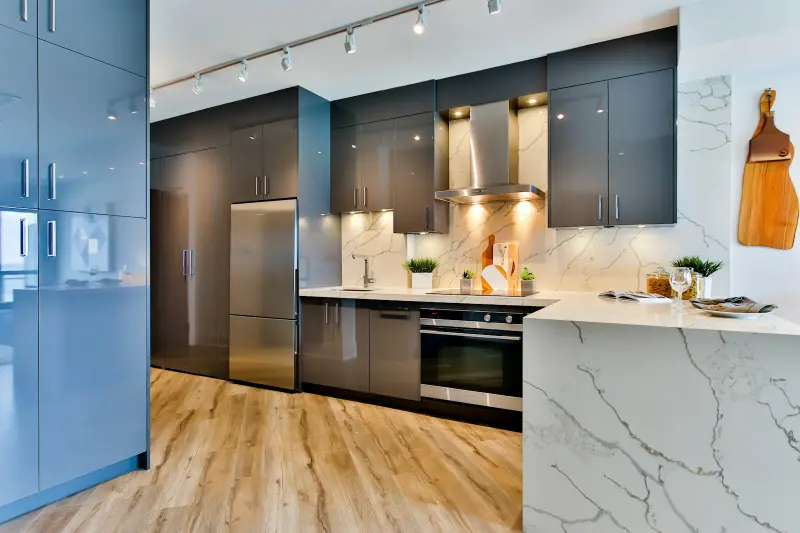 Kitchen with blue and charcoal cabinetry and marble counters